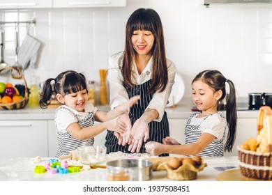 Portrait Of Enjoy Happy Love Asian Family Mother And Little Toddler Asian Girl Daughter Child Having Fun Cooking Together With Baking Cookie And Cake Ingredient On Table In Kitchen