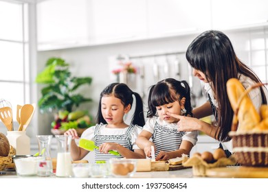 Portrait Of Enjoy Happy Love Asian Family Mother And Little Toddler Asian Girl Daughter Child Having Fun Cooking Together With Baking Cookie And Cake Ingredient On Table In Kitchen