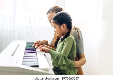 Portrait Of Enjoy Happy Love Asian Family Mother And Little Asian Girl Child Smiling And Having Fun Teaching And Play Piano Music Lesson At Home