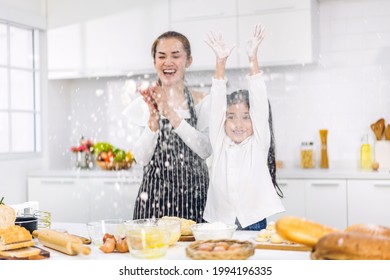 Portrait of enjoy happy love asian family mother and little toddler asian girl daughter child having fun cooking together with dough for homemade bake cookie and cake ingredient on table in kitchen - Powered by Shutterstock