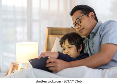 Portrait Of Enjoy Happy Love Asian Family Father And Little Asian Boy Son Smiling Playing And Having Fun Teach Use Tablet Watching Cartoon And Play Game At Home