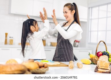 Portrait of enjoy happy love asian family mother and little toddler asian girl daughter child having fun cooking together with dough for homemade bake cookie and cake ingredient on table in kitchen - Powered by Shutterstock