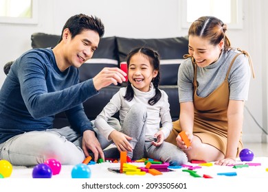 Portrait of enjoy happy love asian family father and mother with little asian girl smiling play with toy build wooden block board game in moments good time at home