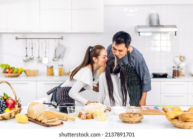 Portrait Of Enjoy Happy Love Asian Family Father And Mother With Little Asian Girl Daughter Child Play And Having Fun Cooking Food Together With Baking Cookie And Cake Ingredient In Kitchen