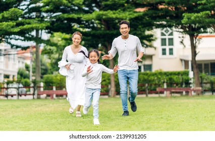 Portrait of enjoy happy love asian family father and mother run with cute little asian girl child smiling play and having fun moments good time in summer park at home