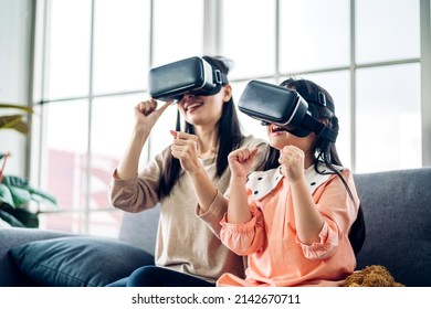 Portrait of enjoy happy love asian family mother and asian girl child smiling and having fun using glasses of of technology virtual reality headset.concept of modern VR metaverse technology - Powered by Shutterstock