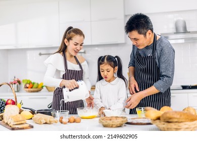 Portrait Of Enjoy Happy Love Asian Family Father And Mother With Little Asian Girl Daughter Child Play And Having Fun Cooking Food Together With Baking Cookie And Cake Ingredient In Kitchen