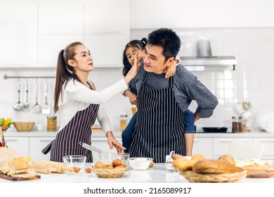 Portrait Of Enjoy Happy Love Asian Family Father And Mother With Little Asian Girl Daughter Child Play And Having Fun Cooking Food Together With Baking Cookie And Cake Ingredient In Kitchen