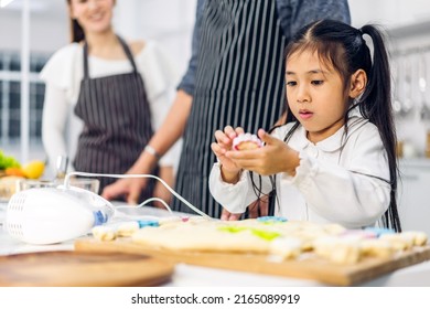 Portrait Of Enjoy Happy Love Asian Family Father And Mother With Little Asian Girl Daughter Child Play And Having Fun Cooking Food Together With Baking Cookie And Cake Ingredient In Kitchen