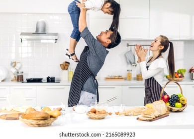 Portrait Of Enjoy Happy Love Asian Family Father And Mother With Little Asian Girl Daughter Child Play And Having Fun Cooking Food Together With Baking Cookie And Cake Ingredient In Kitchen