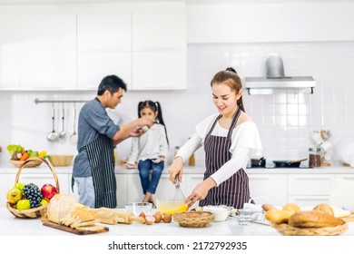 Portrait Of Enjoy Happy Love Asian Family Father And Mother With Little Asian Girl Daughter Child Play And Having Fun Cooking Food Together With Baking Cookie And Cake Ingredient In Kitchen