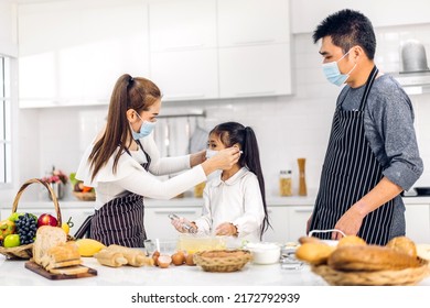 Portrait Of Enjoy Happy Love Asian Family Father And Mother With Little Asian Girl Daughter Child Play And Having Fun Cooking Food Together With Baking Cookie And Cake Ingredient In Kitchen