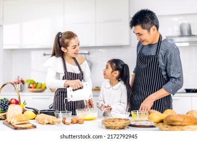 Portrait Of Enjoy Happy Love Asian Family Father And Mother With Little Asian Girl Daughter Child Play And Having Fun Cooking Food Together With Baking Cookie And Cake Ingredient In Kitchen