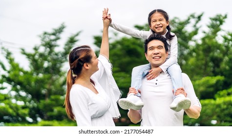 Portrait Of Enjoy Happy Love Asian Family Father And Mother Holding Cute Little Asian Girl Child Smiling Playing And Having Fun Moments Good Time In Summer Park At Home