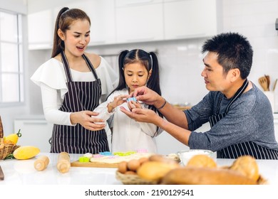 Portrait Of Enjoy Happy Love Asian Family Father And Mother With Little Asian Girl Daughter Child Play And Having Fun Cooking Food Together With Baking Cookie And Cake Ingredient In Kitchen