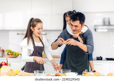 Portrait Of Enjoy Happy Love Asian Family Father And Mother With Little Asian Girl Daughter Child Play And Having Fun Cooking Food Together With Baking Cookie And Cake Ingredient In Kitchen