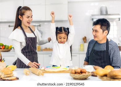 Portrait Of Enjoy Happy Love Asian Family Father And Mother With Little Asian Girl Daughter Child Play And Having Fun Cooking Food Together With Baking Cookie And Cake Ingredient In Kitchen