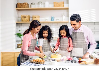 Portrait Of Enjoy Happy Love Asian Family Father And Mother With Little Asian Girl Daughter Child Play And Having Fun Cooking Food Together With Baking Cookie And Cake Ingredient In Kitchen