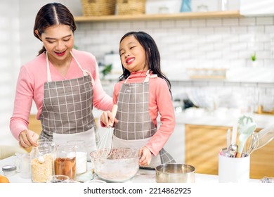 Portrait Of Enjoy Happy Love Asian Family Mother And Little Toddler Asian Girl Daughter Child Having Fun Cooking Together With Dough For Homemade Bake Cookie And Cake Ingredient On Table In Kitchen