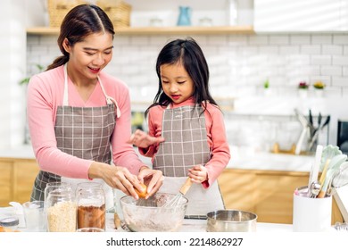 Portrait Of Enjoy Happy Love Asian Family Mother And Little Toddler Asian Girl Daughter Child Having Fun Cooking Together With Dough For Homemade Bake Cookie And Cake Ingredient On Table In Kitchen