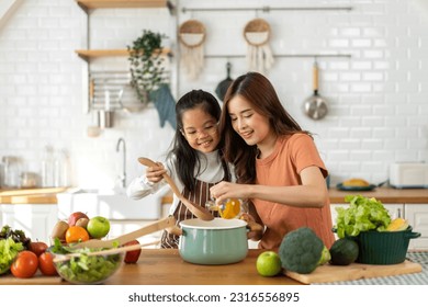 Portrait of enjoy happy love asian family mother with asian girl daughter child help cooking food healthy eat with fresh vegetable testing smell soup in pot with spoon.helping mommy in kitchen at home - Powered by Shutterstock