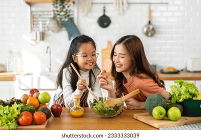 Portrait of enjoy happy love asian family mother and little asian girl daughter child having fun help cooking food healthy eat together with fresh vegetable salad and ingredient in kitchen - Powered by Shutterstock