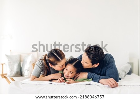 Portrait of enjoy happy love asian family father and mother holding hug cute little asian girl child smiling play and having fun moments good time in at home	