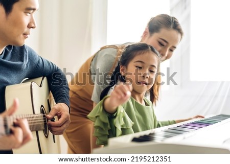 Portrait of enjoy happy love asian family mother and little asian girl child smiling and having fun teaching and play piano music lesson at home	