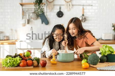 Portrait of enjoy happy love asian family mother with little asian girl daughter child help cooking food healthy eat with vegetable testing smell soup in a pot with spoon.helping mommy in kitchen