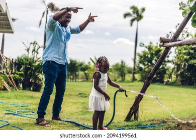 Portrait Of Enjoy Happy Love Black Family African American Father And  Little African Girl Child Smiling And Watering Garden Grass With Rubber Strap In Summer Park At Home