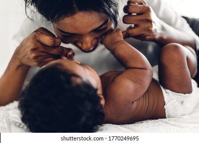 Portrait Of Enjoy Happy Love Family African American Mother Playing With Adorable Little African American Baby.Mom Touching With Cute Son Moments Good Time In A White Bedroom.Love Of Black Family 