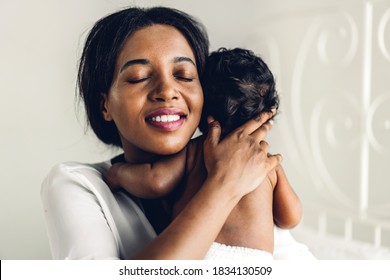 Portrait Of Enjoy Happy Love Family African American Mother Playing With Adorable Little African American Baby.Mom Hug With Cute Son Moments Good Time In A White Bedroom.Love Of Black Family Concept