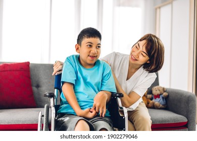 Portrait Of Enjoy Happy Love Family Asian Mother Playing And Carer Helping Look At Disabled Son Child Sitting In Wheelchair Moments Good Time At Home.disability Care Concept