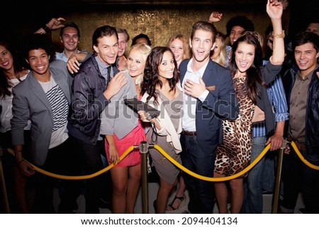 Portrait of enthusiastic crowd waiting in queue outside nightclub