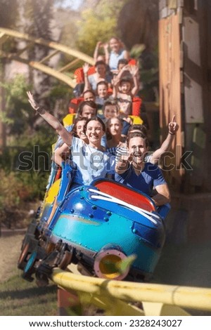 Portrait enthusiastic friends cheering riding roller coaster at amusement park