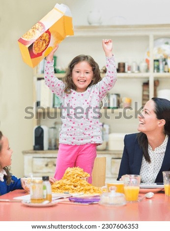 Portrait enthusiastic girl cheering with cereal box at breakfast table