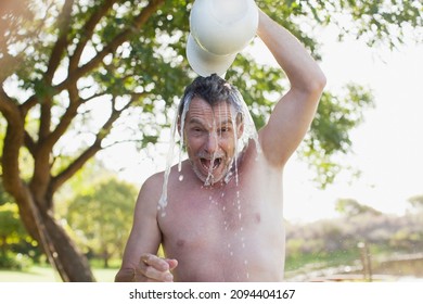 Portrait Of Enthusiastic Man Pouring Water Overhead