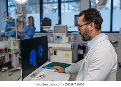 Portrait of ER doctor in hospital working in emergency room. Healthcare worker looking at MRI scan on medical computer in emergency room. - Powered by Shutterstock