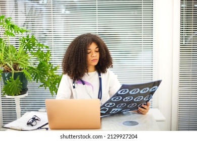 Portrait Of Ethnic Female Doctor Analyzing X-ray Or MRI Scan While Working In Hospital, Selective Focus. Physician Looking At CT Screening, Using Diagnostic Tool For Detecting Lung Diseases