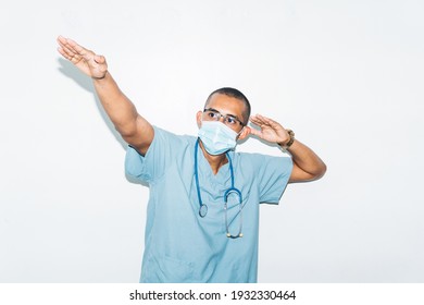 Portrait Of An Euphoric And Positive Hispanic Ethnicity Male Doctor Wearing Mask Making A Victory Gesture. Happy Concept.