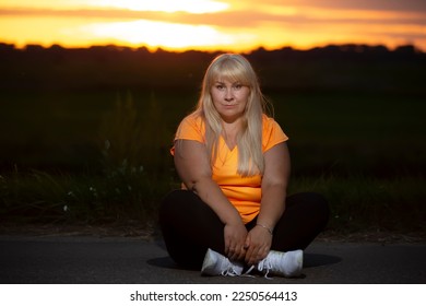 Portrait of a European middle-aged woman in a tracksuit, posing for the camera, relaxing. excited overweight woman in trendy tracksuit resting after exercising. - Shutterstock ID 2250564413