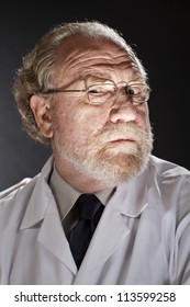 Portrait Of Evil Doctor In Lab Coat And Necktie With Sinister Expression. Dark Background And Dramatic Low Angle Spot Lighting Create Spooky Shadows On Face.