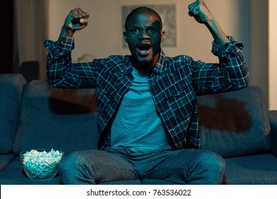 Portrait Of Excited African American Man Watching Tv At Home