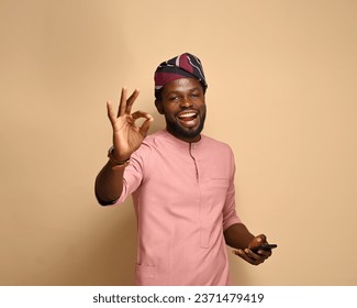 Portrait of an excited African man holding a smartphone, with his hands giving approval signs. mobile phone with empty space, copy space for Advertisement