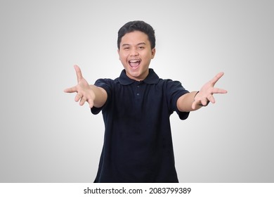 Portrait Of Excited Asian Man In Black Polo Shirt Looking Something He Has Been Wanting For A Long Time. Hug And Welcoming Something. Isolated Image On Gray Background