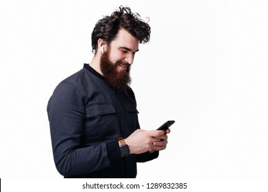 Portrait Of Excited Bearded Man Using His Phone And Wearing Airpods