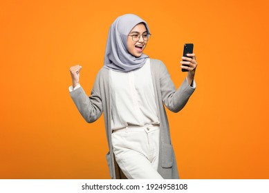 Portrait Of Excited Beautiful Asian Woman While Looking At Smartphone