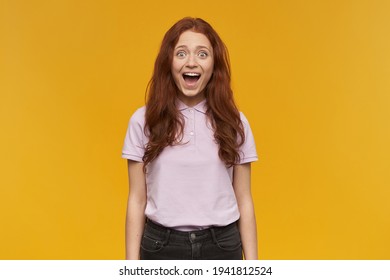 Portrait Of Excited, Beautiful Lady With Long Ginger Hair. Wearing Pink T-shirt. People And Emotion Concept. Surprised To See You. Watching At The Camera, Isolated Over Orange Background