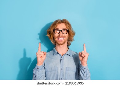 Portrait of excited cheerful man look indicate fingers up empty space proposition isolated on blue color background