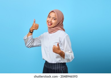 Portrait of excited cheerful young Asian woman showing thumbs up or approval sign